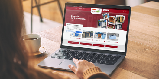 Junge Frau betrachtet den Gartenhaus-Online Shop auf einem Laptop